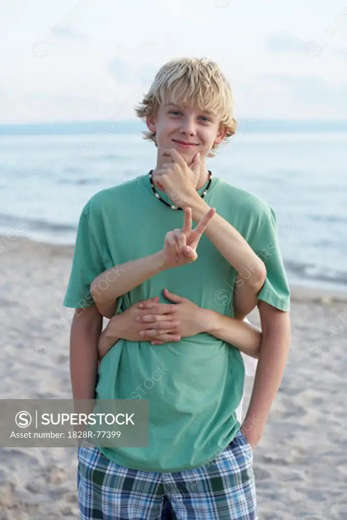 Boy Standing on the Beach, Children Standing Behind Him Making Hand Gestures
