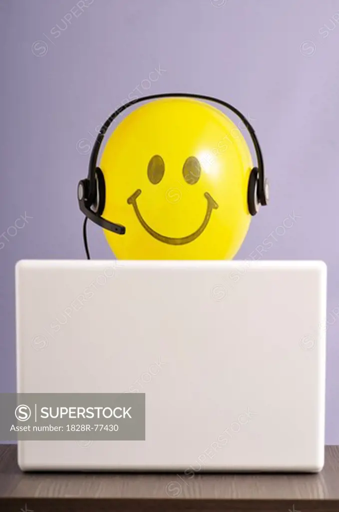 Smiley Face Balloon With Headset at Laptop Computer