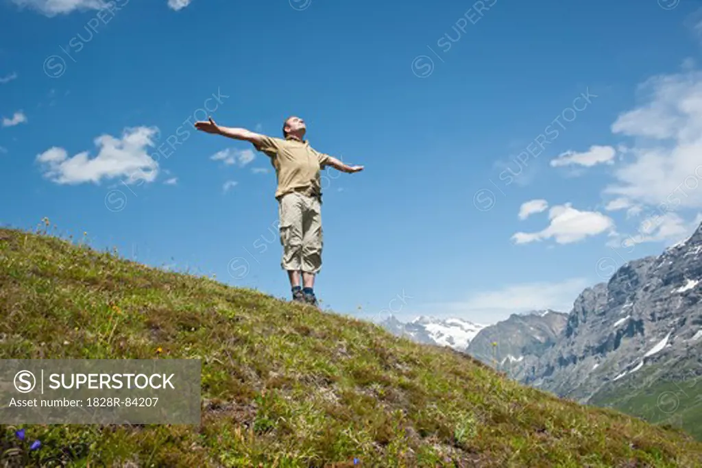 Man Standing on Mountain Side with Arms Outstretched, Bernese Oberland, Switzerland