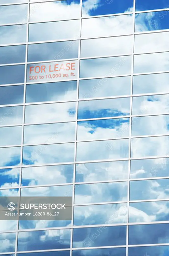 Sky and Clouds Reflected in Building Windows with For Lease Sign