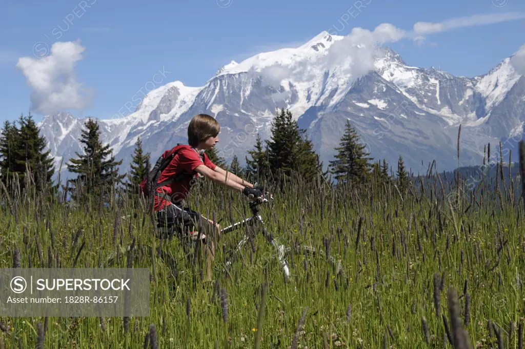 Boy Riding Bicycle in Mountains, Alps, France