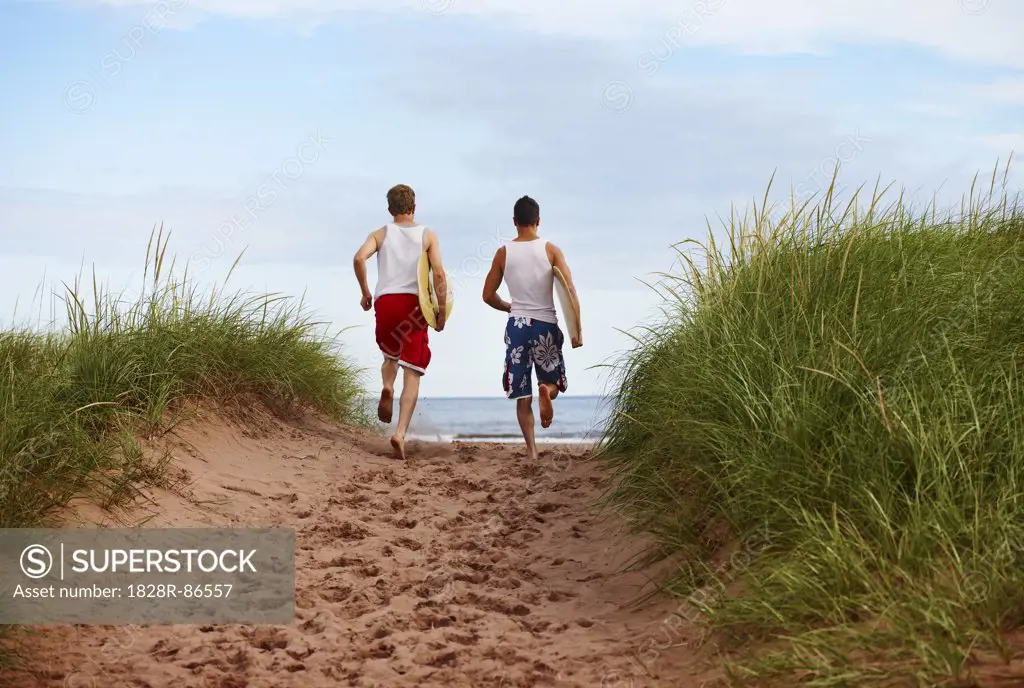 Young Men holding Skimboards while Running to Beach, PEI, Canada