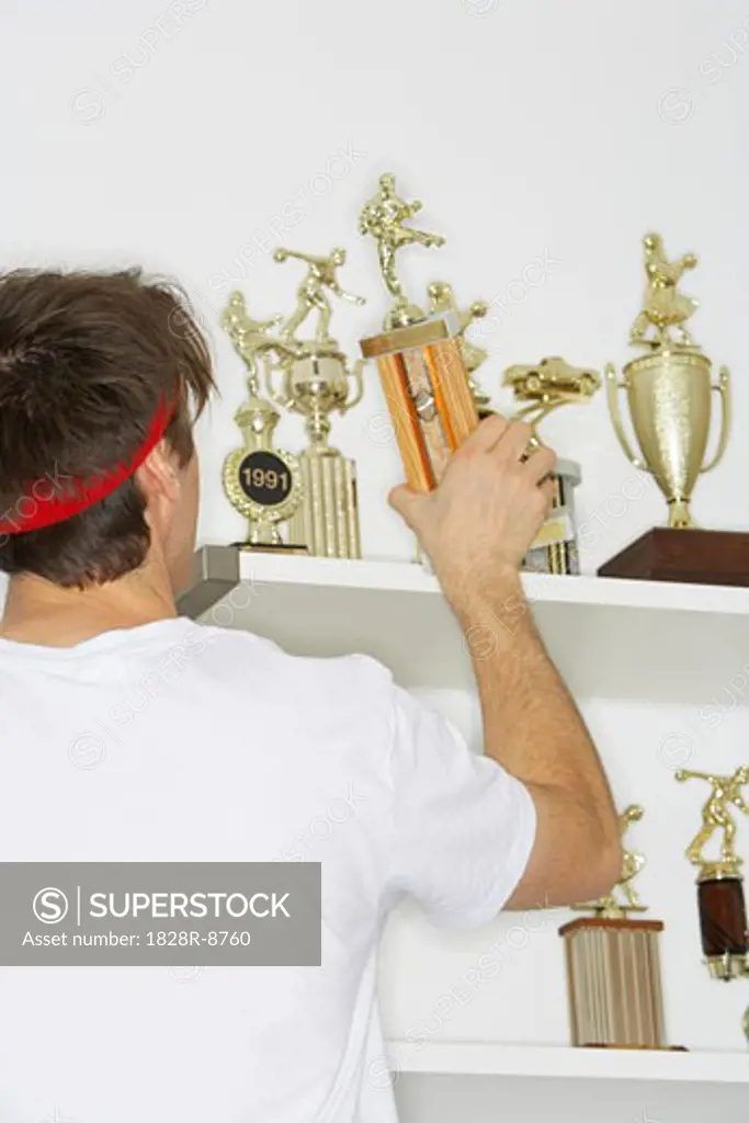 Man Placing Trophies on Shelf   