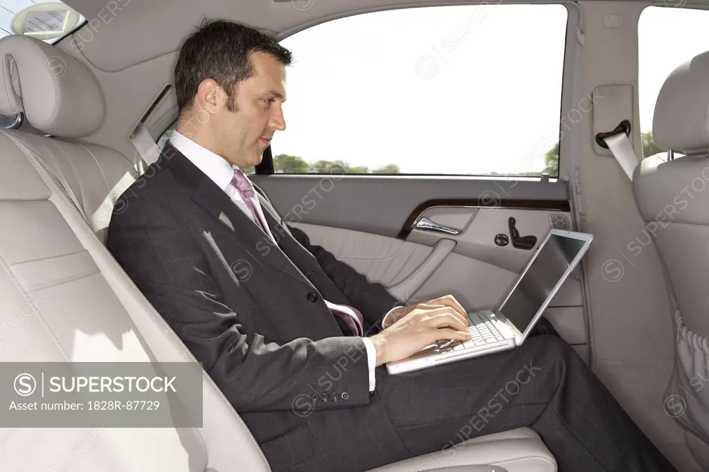 Businessman Using Laptop Computer in Car