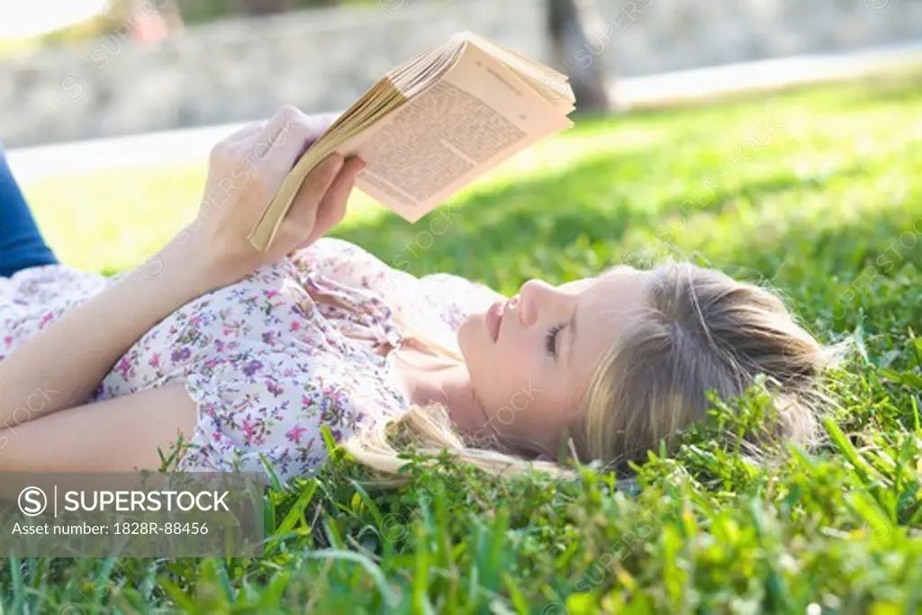 Close-up of Woman Lying on Grass, Reading Book