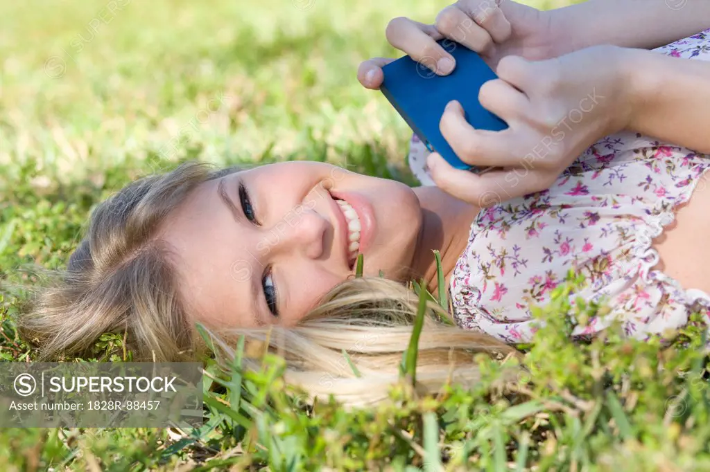 Close-up Portrait of Woman Lying on Grass holding Cell Phone