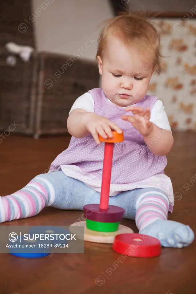 Baby Girl Sitting on Floor Playing with Toy