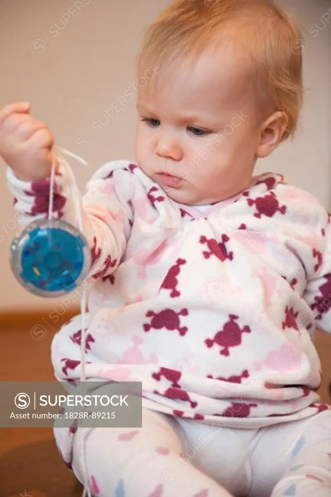 Baby Girl Sitting on Floor Playing with Yo-Yo