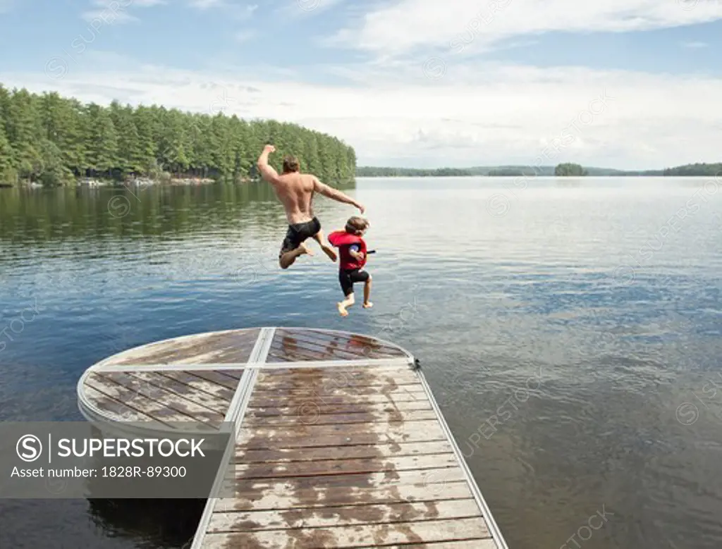 Father and Son Jumping in Lake, Belgrade Lakes, Maine, USA