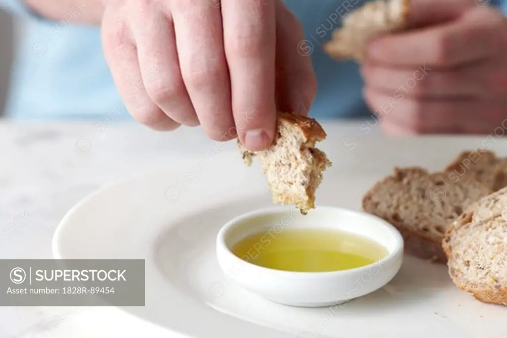 Man Dipping Baguette into Olive Oil