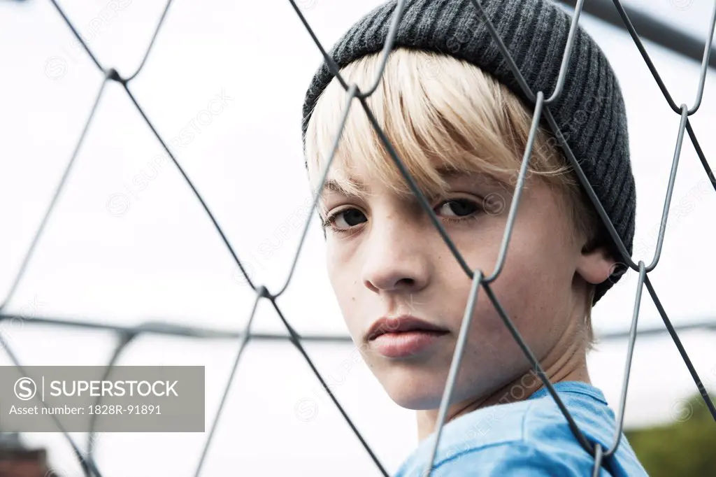 Portrait of Boy Looking Through Chain Link Fence, Mannheim, Baden-Wurttemberg, Germany