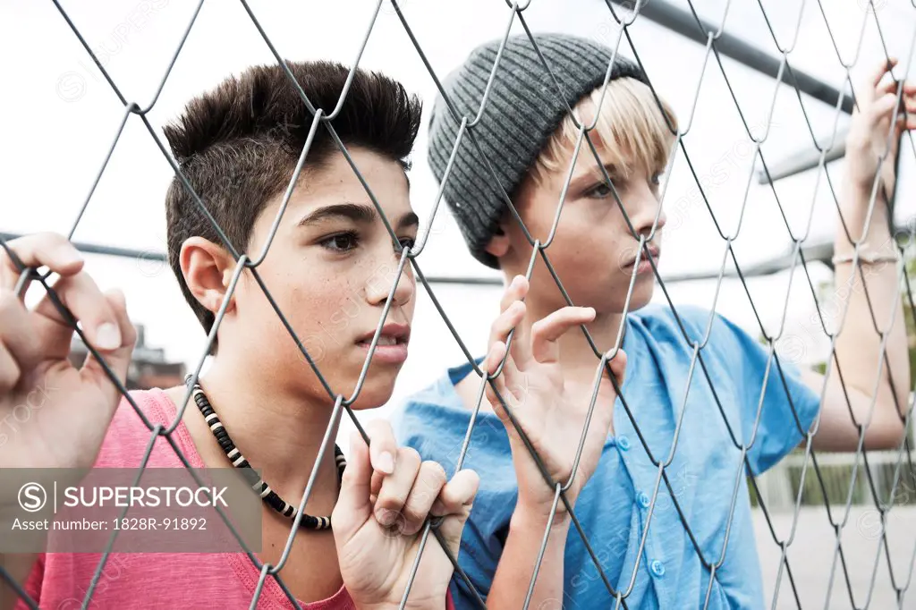 Two Boys Looking Through Chain Link Fence, Mannheim, Baden-Wurttemberg, Germany