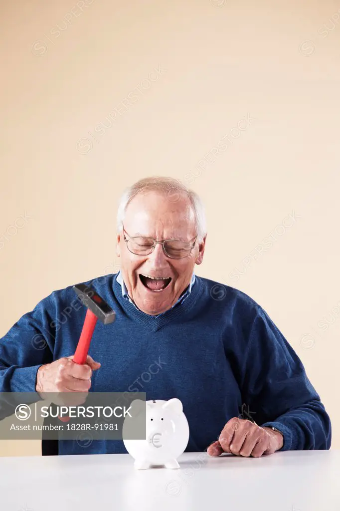 Portrait of Senior Man Breaking Piggy Bank