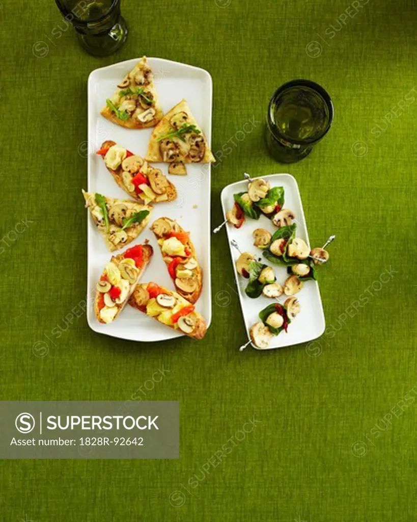 Overhead View of Mushroom Appetizers on Trays with Drinking Glasses on Green Background in Studio