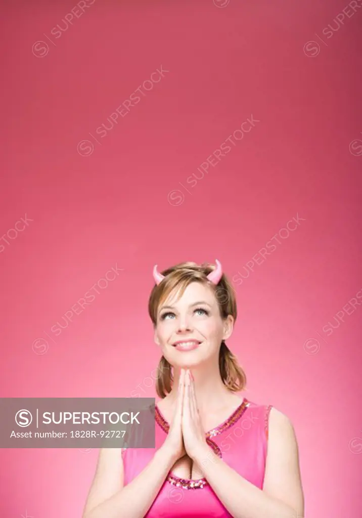Portrait of Woman Wearing Devil Horns Looking Up and Praying