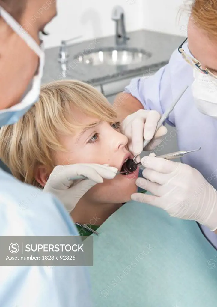 Dentist and Hygienist checking Boy's Teeth during Appointment, Germany