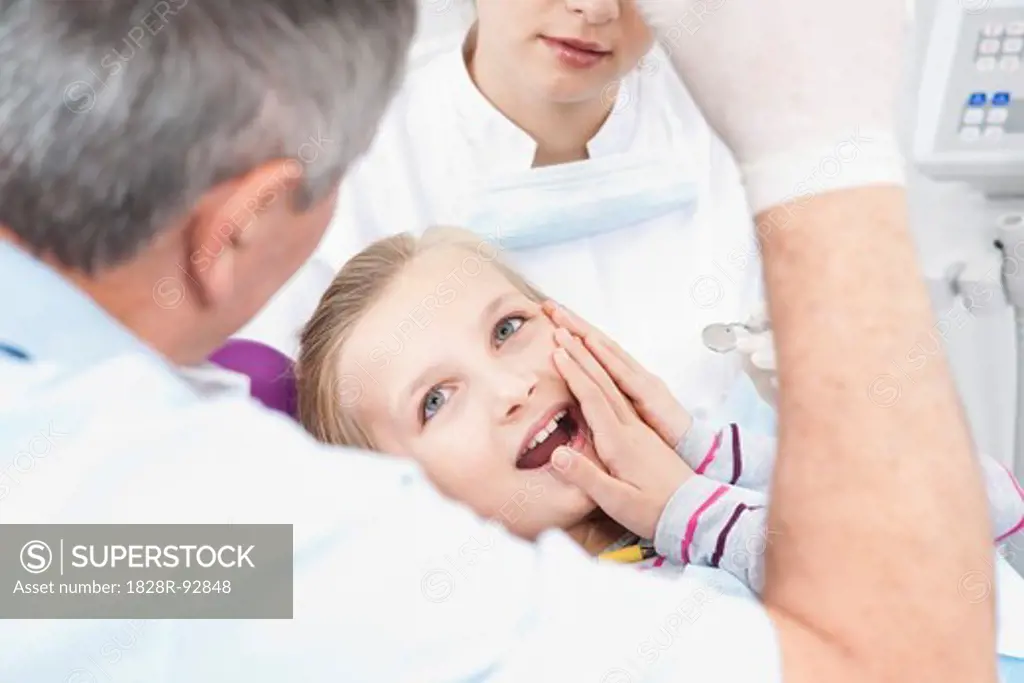 Girl touching Cheek with Dentist and Hygienist in Dental Office, Germany