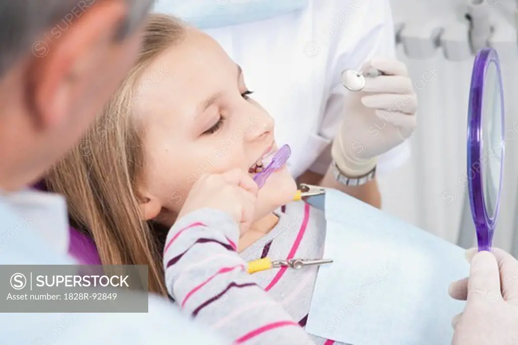 Girl Brushing Teeth with Dentist and Hygienist during Appointment, Germany