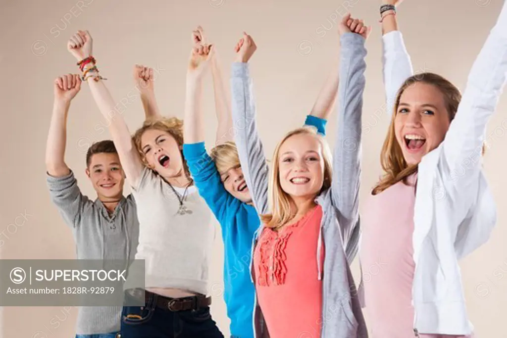 Portrait of Group of Teenage Boys and Girls with Arms in Air, Smiling and Looking at Camera, Studio Shot on White Background