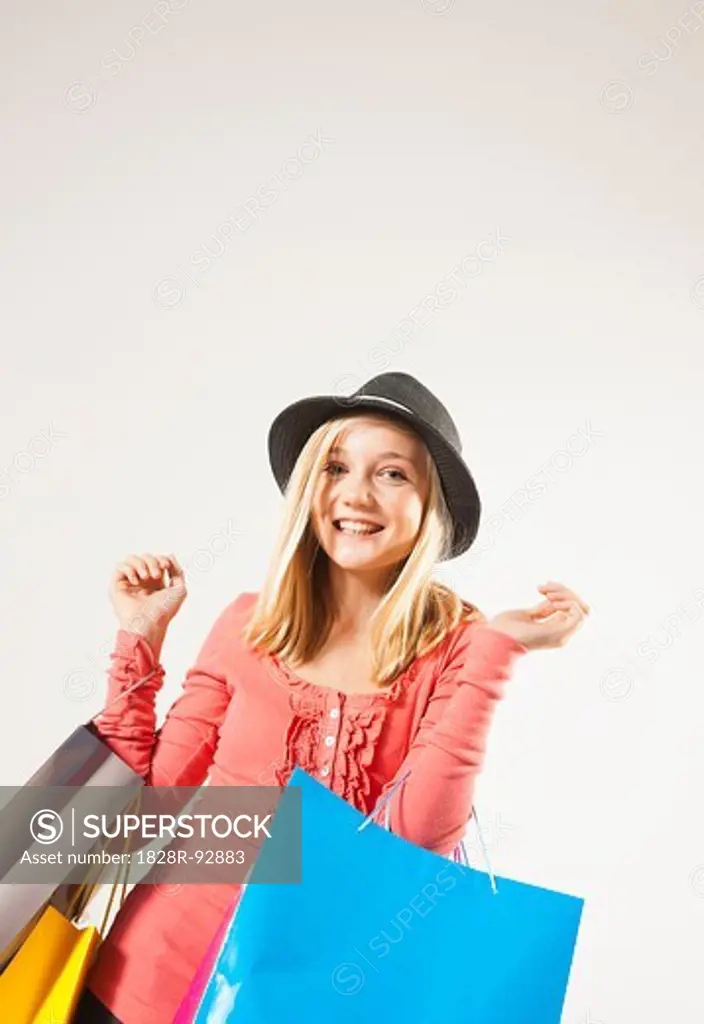 Low Angle View Portrait of Blond, Teenage Girl with Straight Hair holding Shopping Bags and Smiling at Camera, Studio Shot on White Background