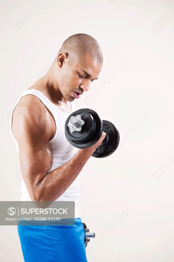 Man Wearing Work Out Clothes and Lifting Weights in Studio with White Background