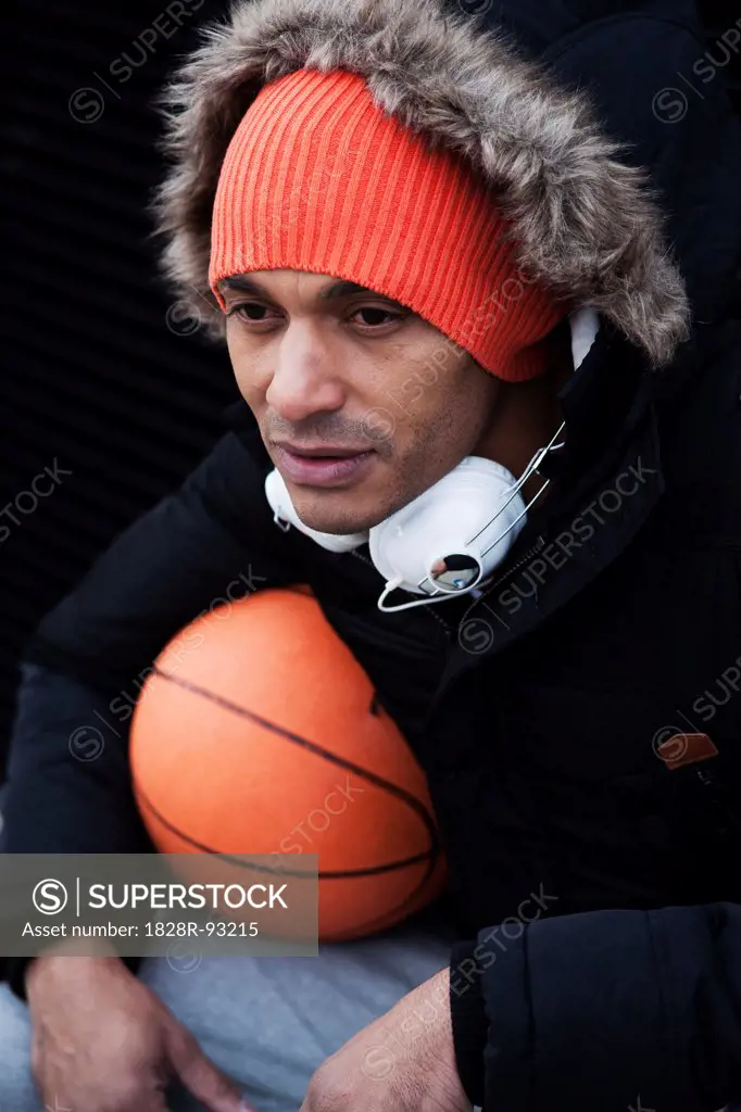 Portrait of Man Outdoors with Headphones on his Neck Holding Basketball, Mannheim, Baden-Wurttemberg, Germany