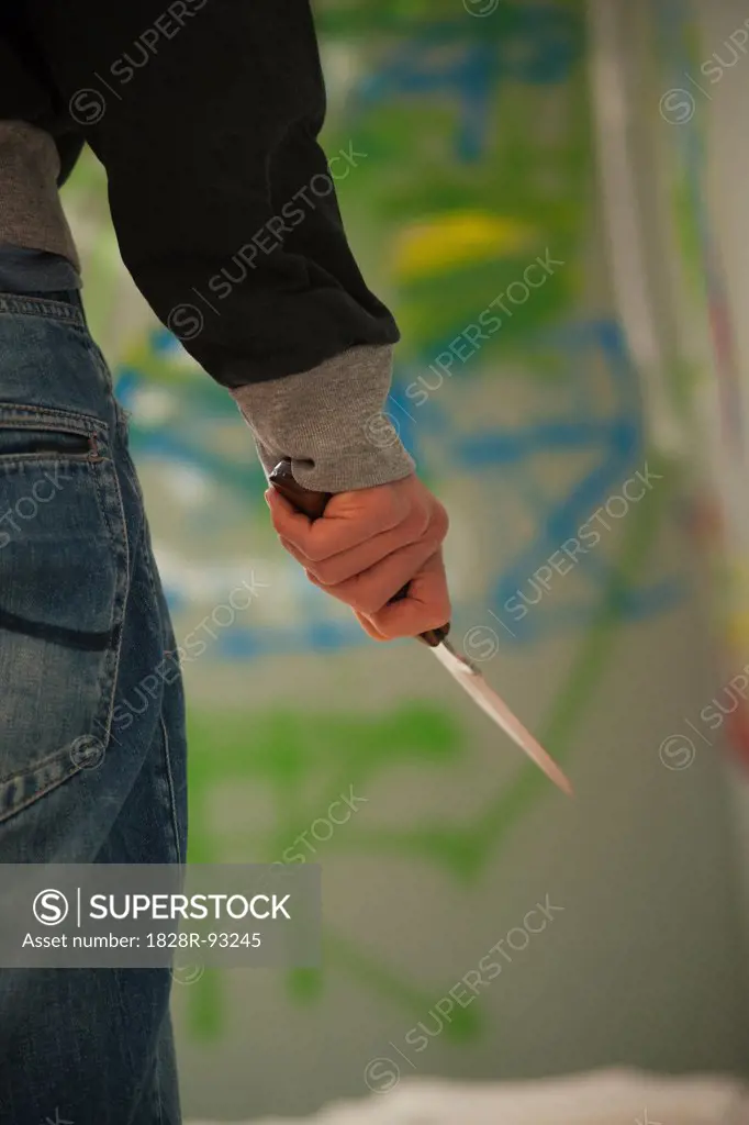 Close-up of Young Man Holding Knife with Grafitti in Background, Mannheim, Baden-Wurttemberg, Germany