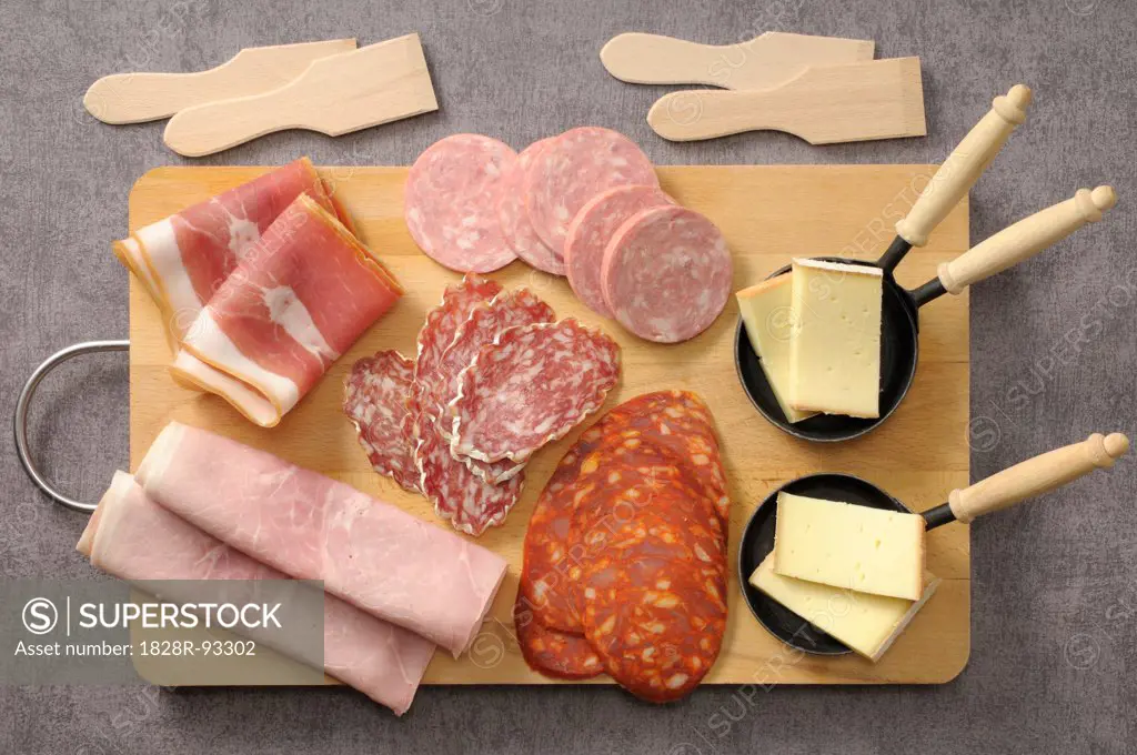 Overhead View of Meats and Cheese for Raclette on Cutting Board on Grey Background, Studio Shot