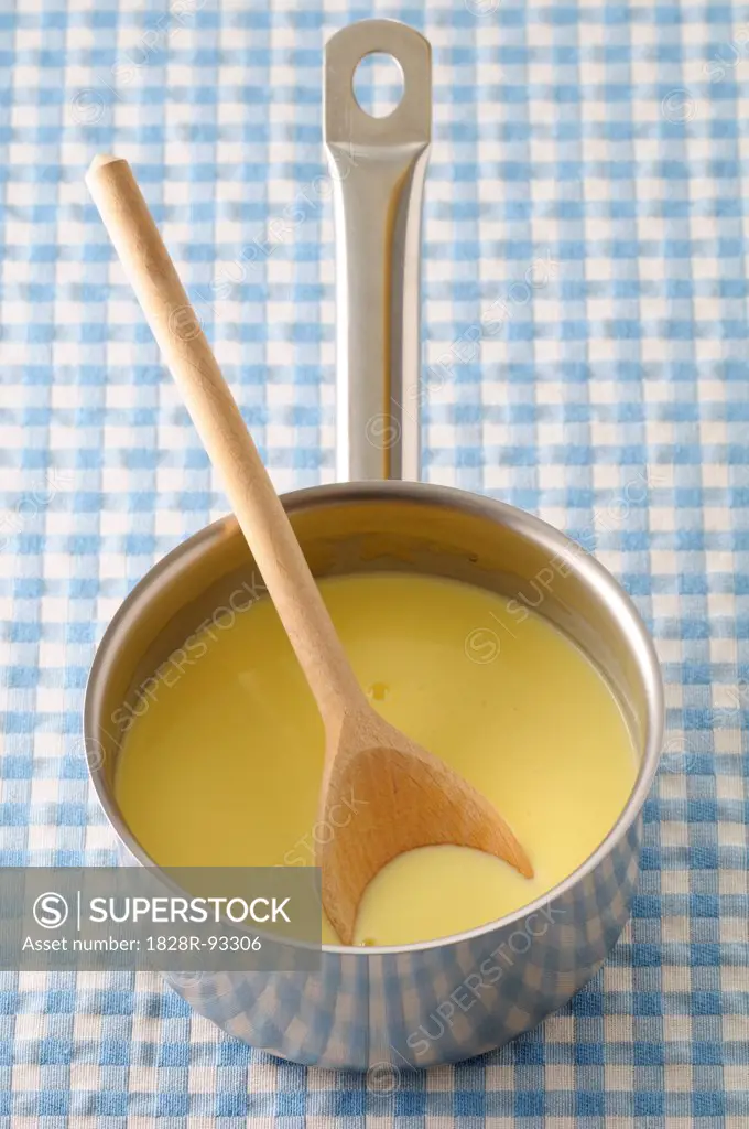 Overhead View of Vanilla Sauce and Wooden Spoon in Cooking Pot on Blue Gingham Background, Studio Shot