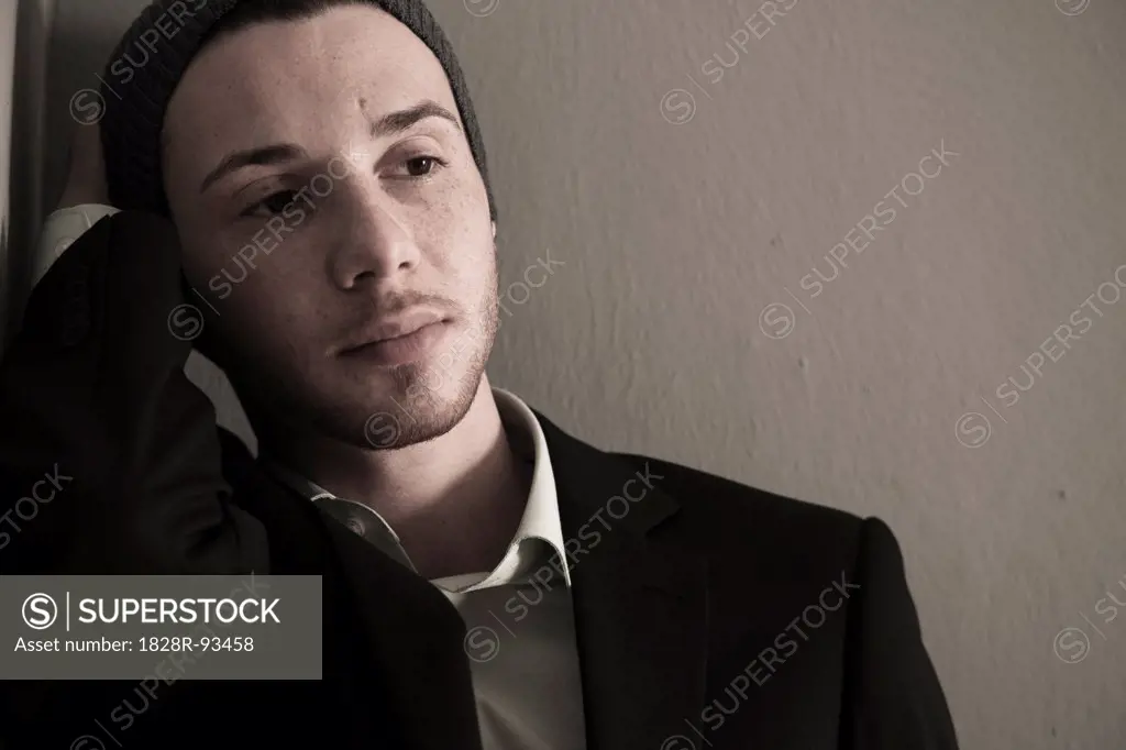 Portrait of Young Man wearing Woolen Hat and Suit Jacket, Looking to the Side, Absorbed in Thought, Studio Shot