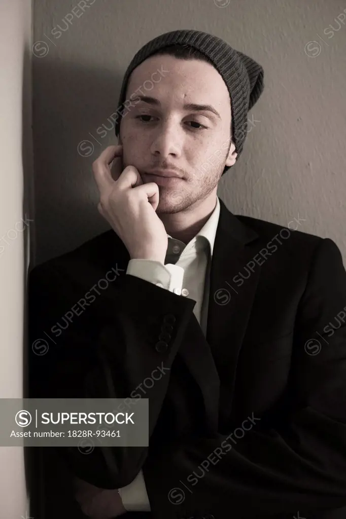 Portrait of Young Man wearing Woolen Hat and Suit Jacket, Looking Downward, Absorbed in Thought, Studio Shot