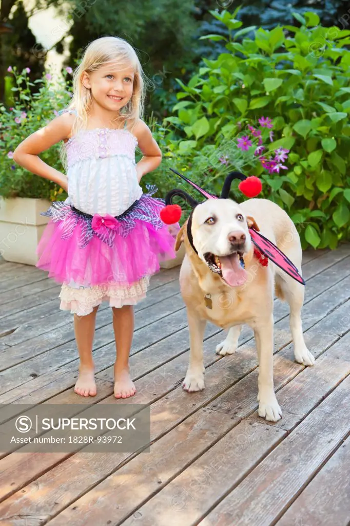 Young girl playing dress up with dog on a sunny summer afternoon in Portland, Oregon, USA