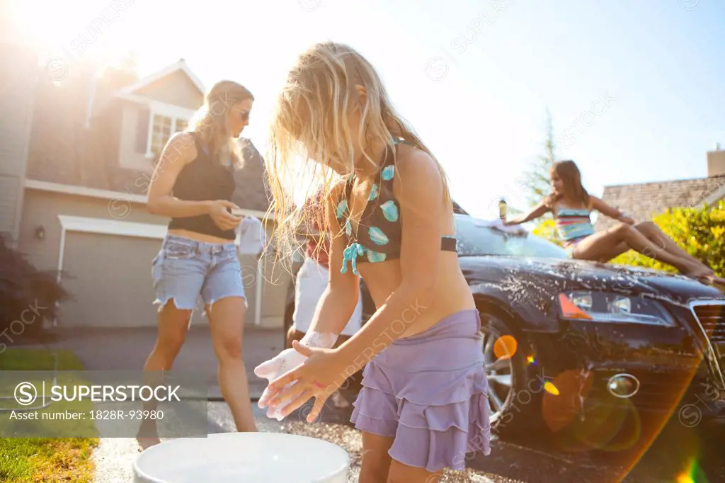 Family washing their car in the driveway of their home on a sunny summer afternoon in Portland, Oregon, USA