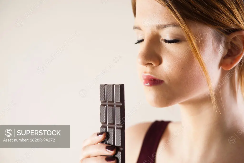Teenage Girl holding Chocolate with Eyes Closed, Studio Shot on White Background