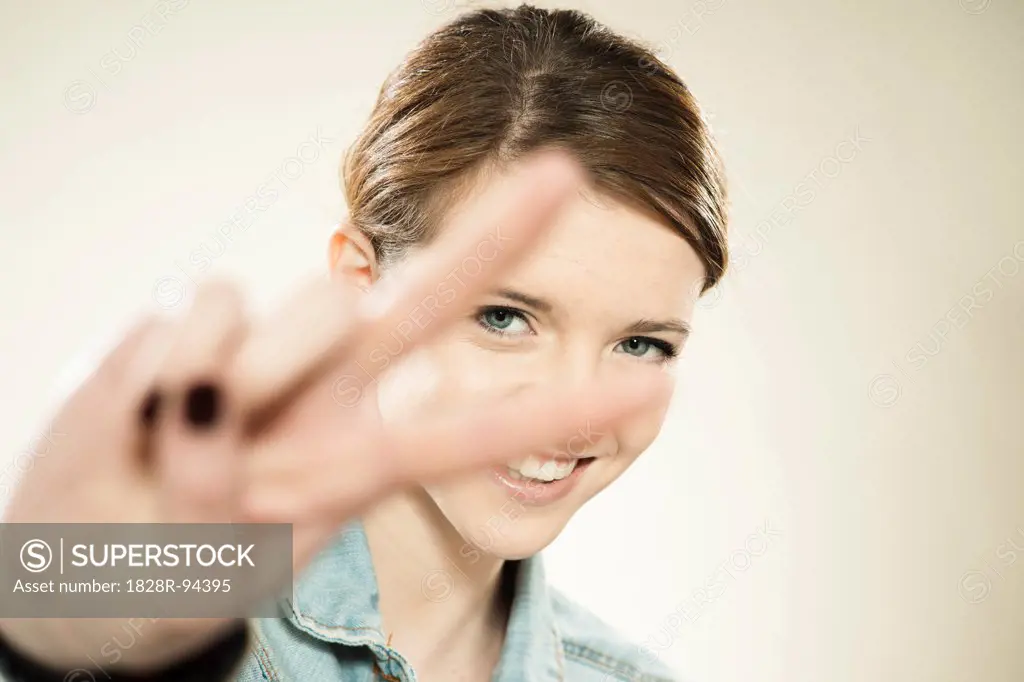 Portrait of Teenage Girl Making the Peace Sign with Her Fingers, in Studio