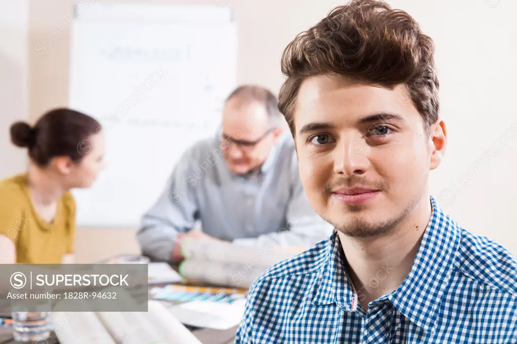 Portrait of Young Businessman with Colleagues Meeting in the Background
