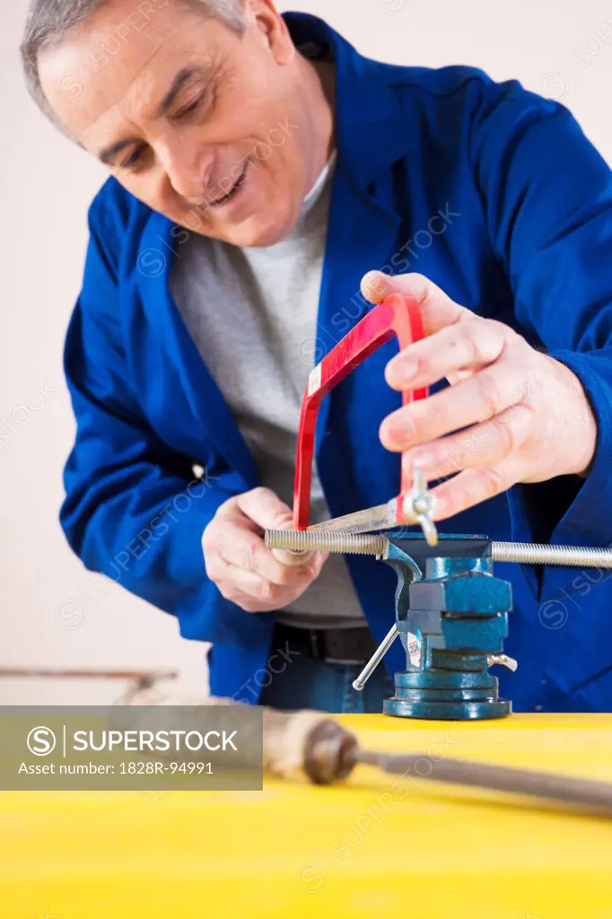 Man Cutting a Pipe for a Plumbing Project, in Studio