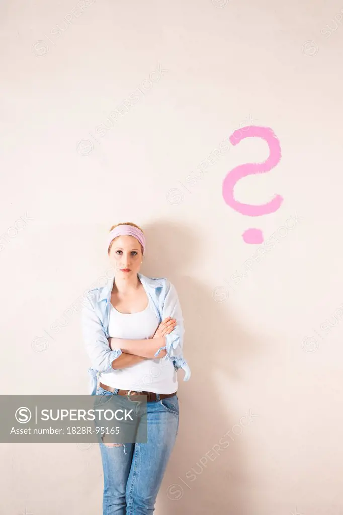 Studio Shot of Young Woman Leaning Against Wall with Question Mark