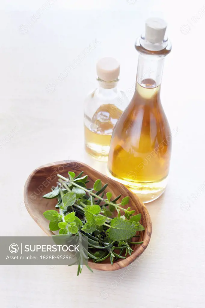 Fresh herbs in a bowl and bottles of oil for aromatherapy, elevated view