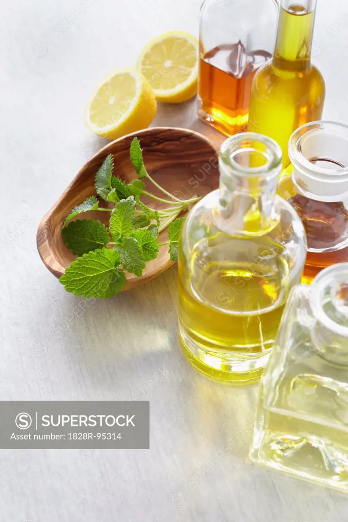 Sprig of lemon balm in a bowl, herbs, lemon and bottles of essential oil
