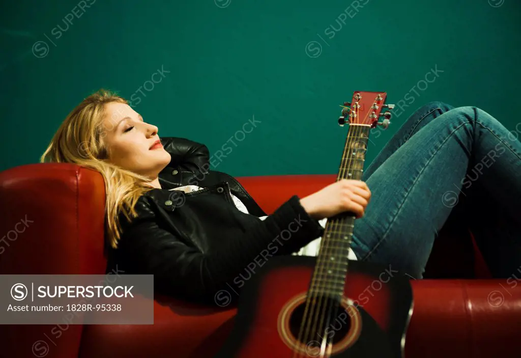 Woman Lying on Sofa and Holding Acoustic Guitar