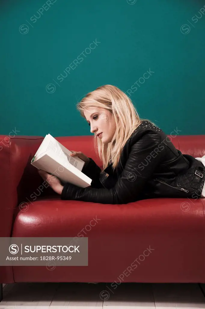 Woman Lying on Sofa and Reading a Book