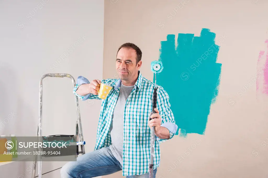 Mature Man having Coffee Break from Renovating his Home by Painting the Walls
