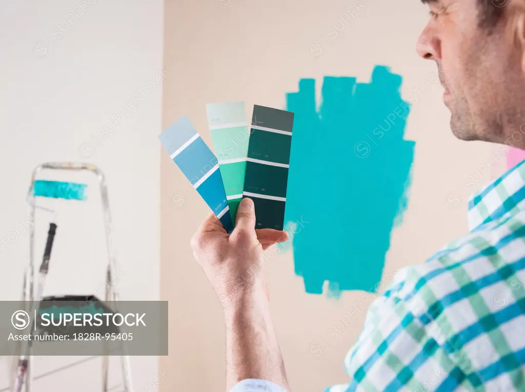 Over the Shoulder View of Mature Man Rrenovating his Home and Looking at Paint Samples
