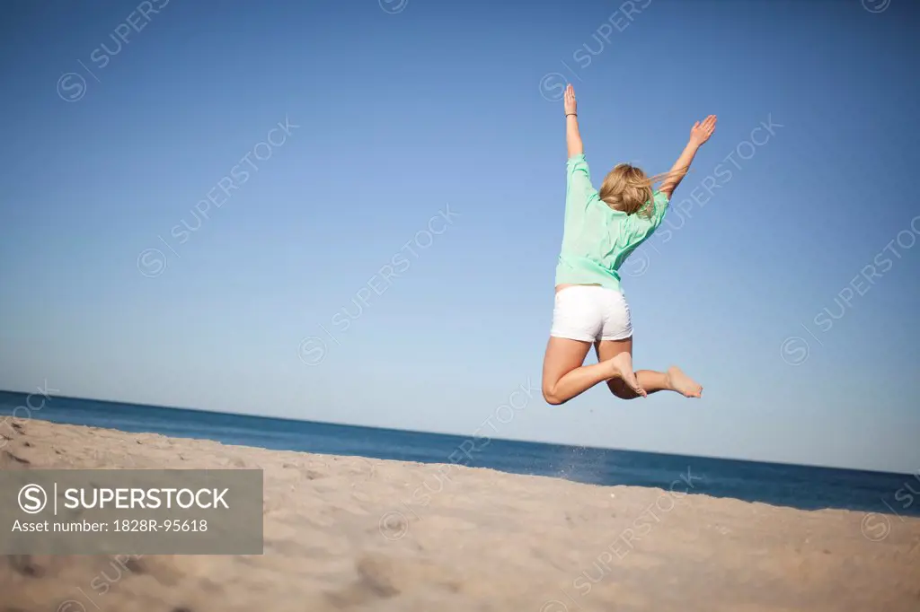 Back View of Young Woman Jumping on Beach, Palm Beach Gardens, Palm Beach County, Florida, USA,03/06/2013