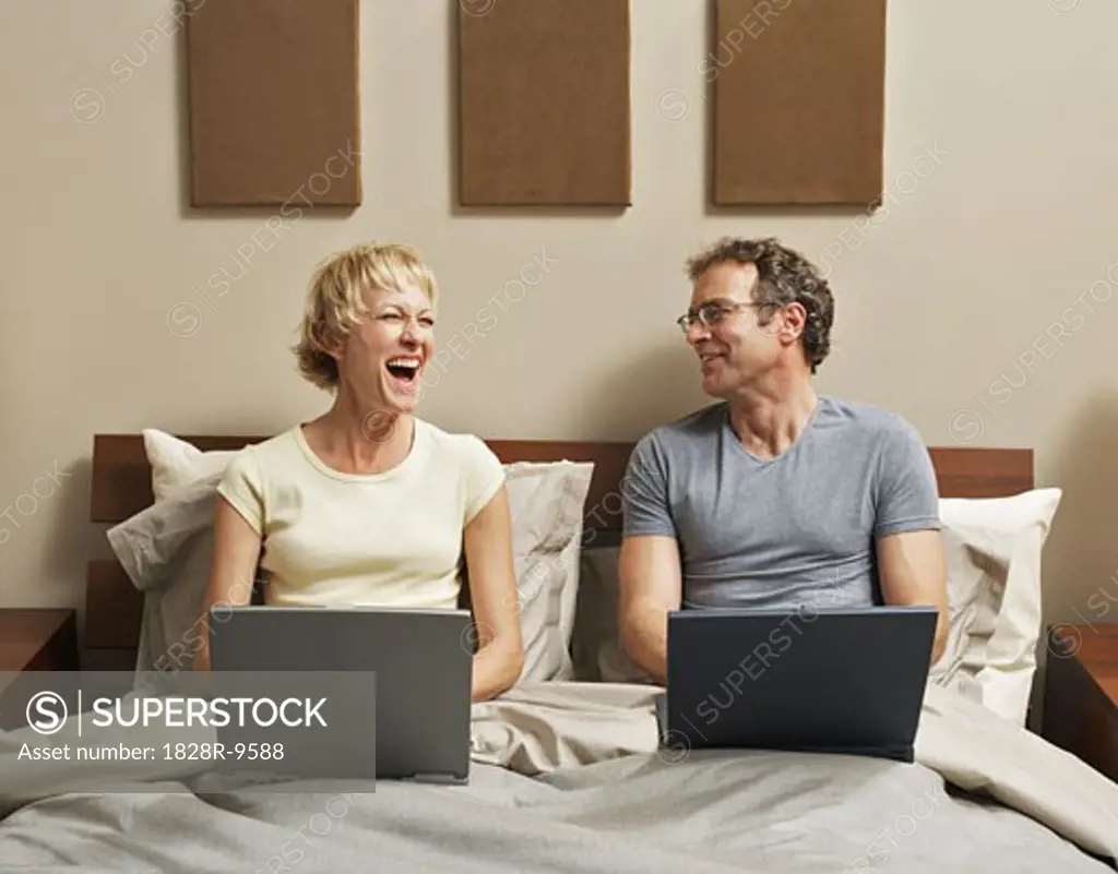 Couple Using Laptop Computers in Bed   