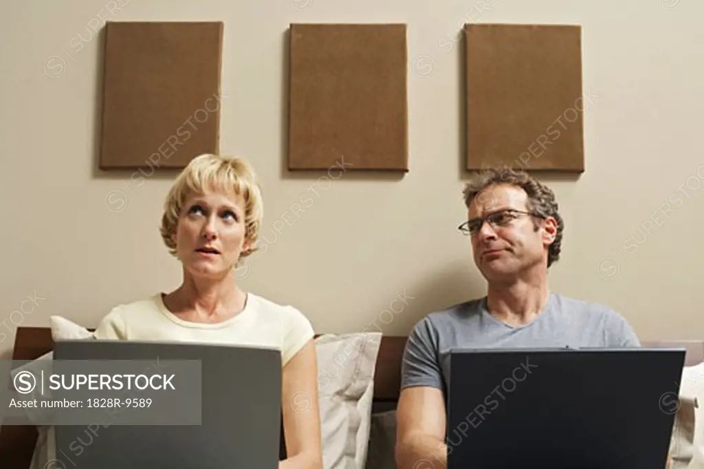 Couple Using Laptop Computers in Bed   