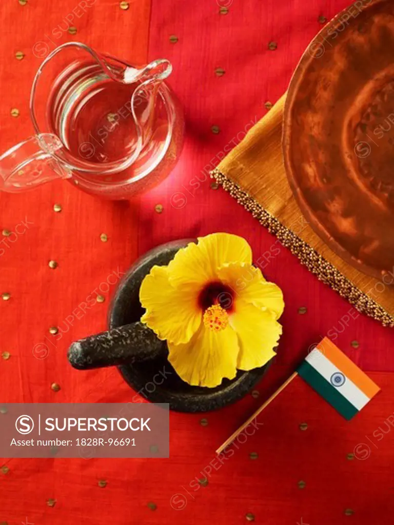 Hibiscus Flower in Mortar with Pestle, Jug of Water and Indian flag on Red Background,03/30/2011