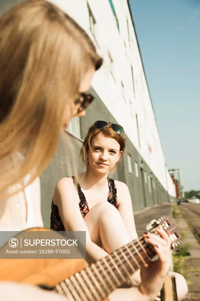 Young women sitting outdoors, hanging out and playing guitar, Mannheim, Germany,05/05/2013