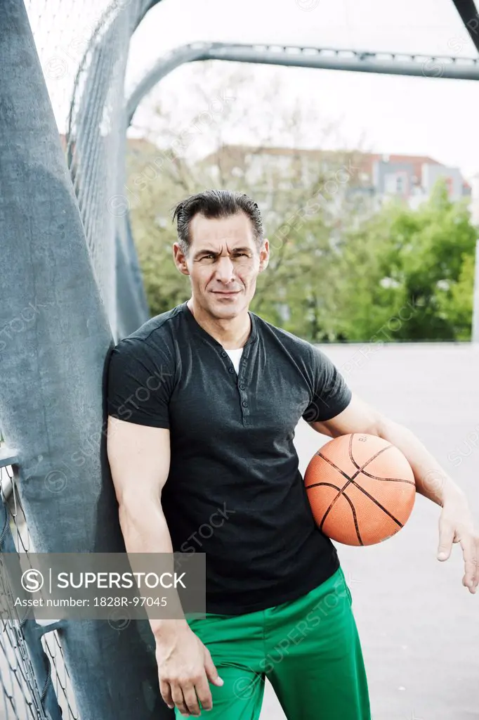 Portrait of mature man standing on outdoor basketball court, Germany,05/02/2013